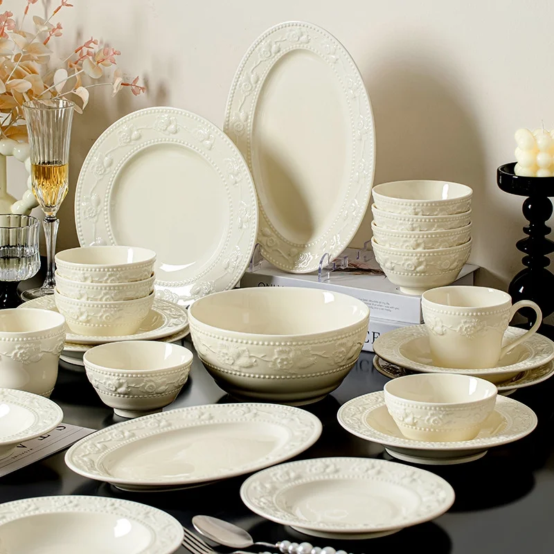 Set of bowls, plates and cutlery with embossed designs. Ceramic dinnerware set including plates, bowls and dishes.