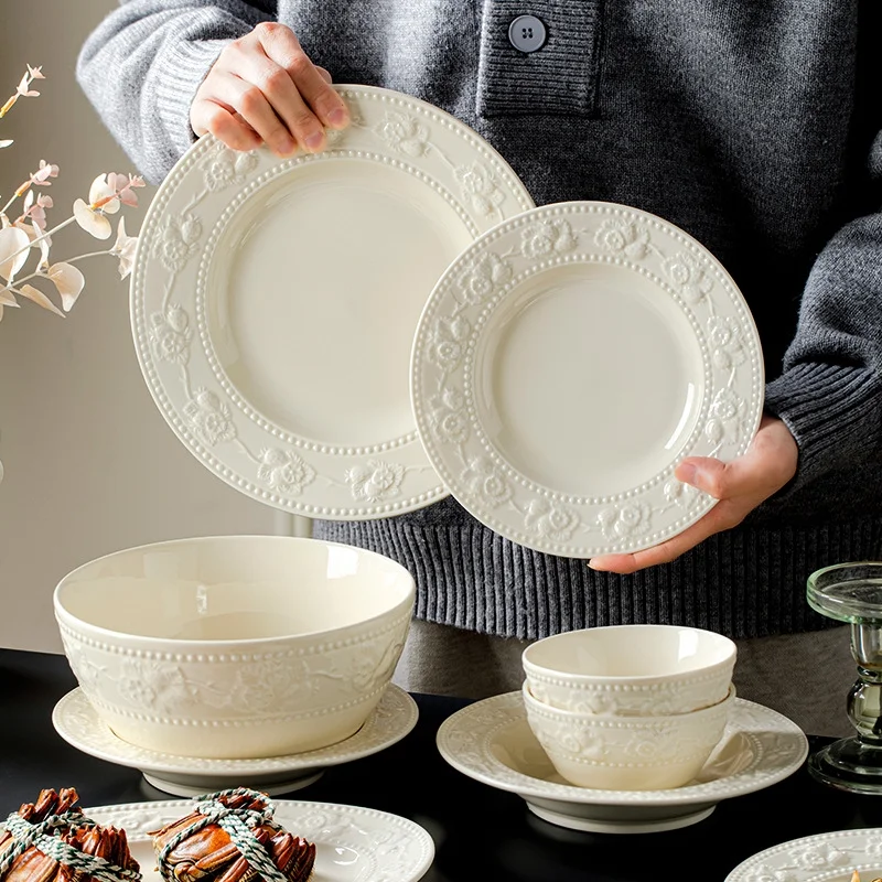 Set of bowls, plates and cutlery with embossed designs. Ceramic dinnerware set including plates, bowls and dishes.